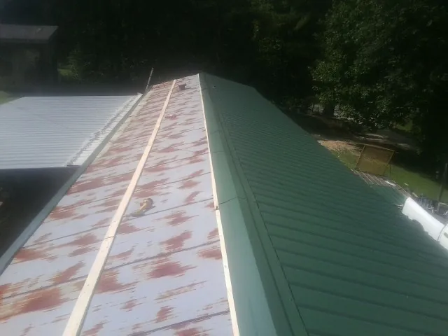 Old rusted panels beside newly installed green metal roofing — Wind Damage Roof Repair by Roofing Brothers in Newport Beach