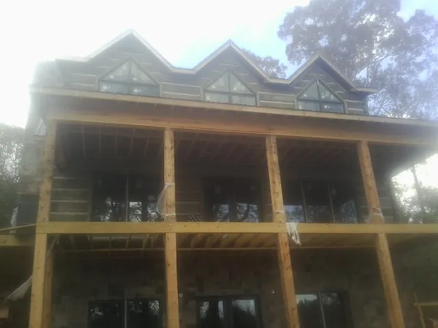 Dormers and porch framing on a large log home under construction — Roof Coating work by our crew in Newport Beach