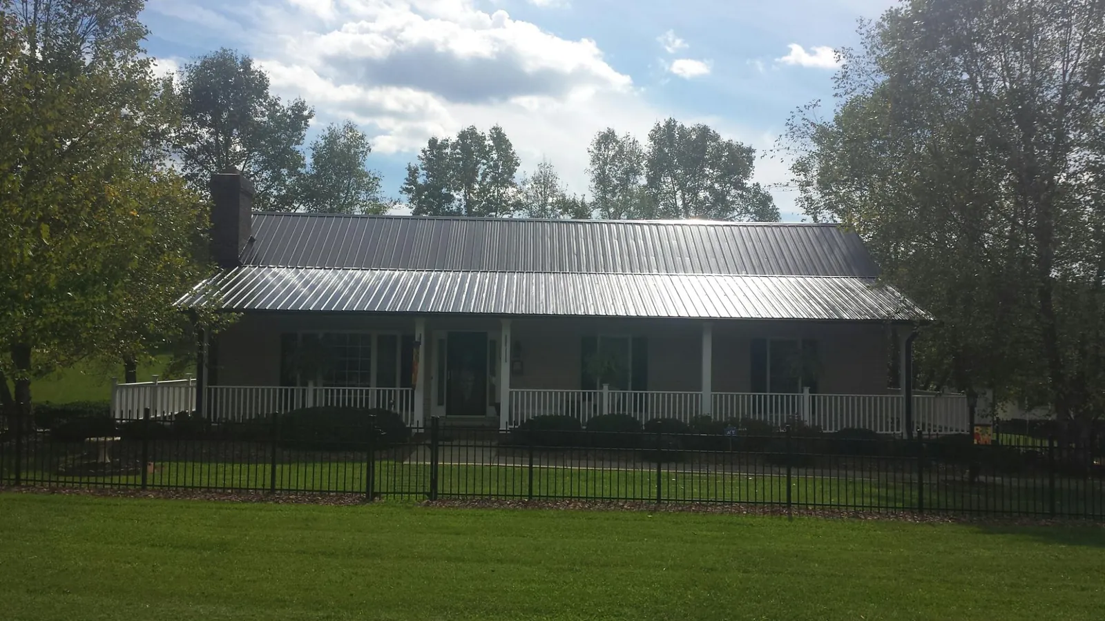 Gray metal roof on a brick ranch with a full width front porch — Gutter Guard Installation work by our crew in Newport Beach