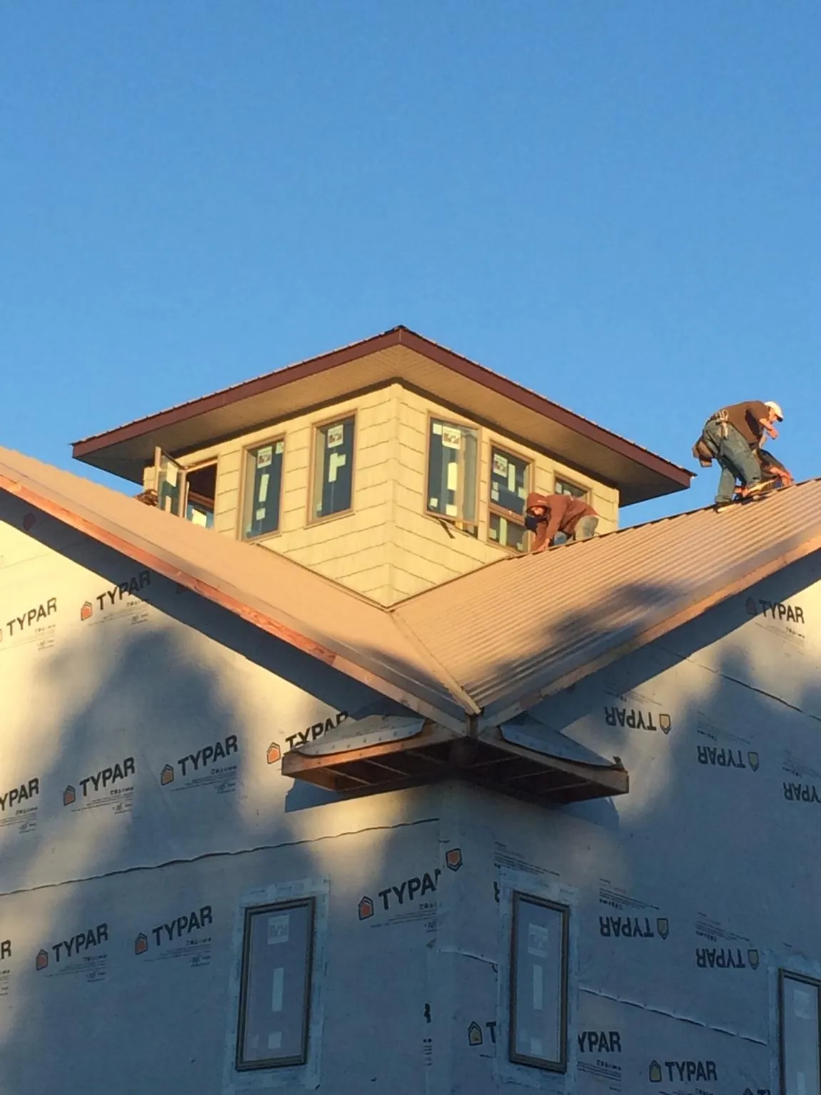 Roofers working around a rooftop cupola on a new metal roof at sunset — Roof Waterproofing in Newport Beach by Roofing Brothers